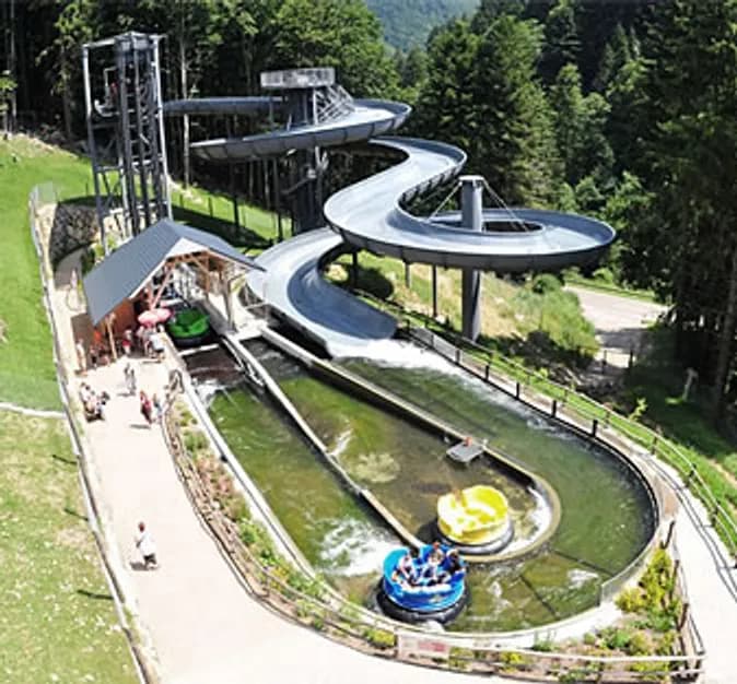 Wasserbahn mit geschwungener Schiene über einer grünen Wiese im Steinwasen-Park