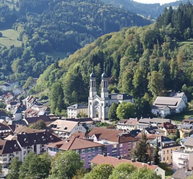Todtnau von oben — Kirchturm und rote Ziegeldächer eingebettet in bewaldete Hänge